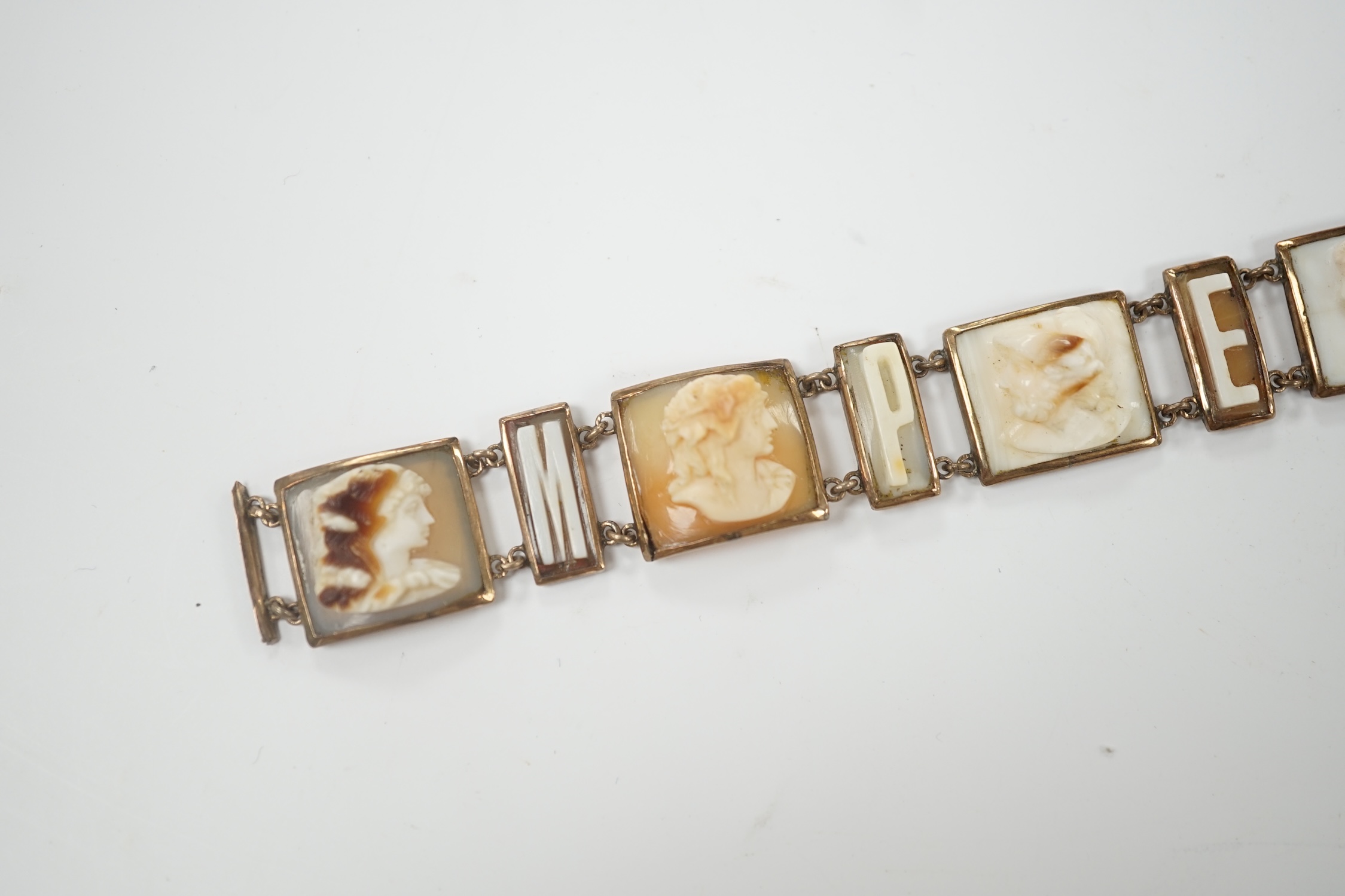 A 19th century Italian? yellow metal overlaid and cameo shell set bracelet, with panels of letters spelling 'Pompei' and panels of busts carved to dexter and sinister, (a.f.), overall 16.8cm.